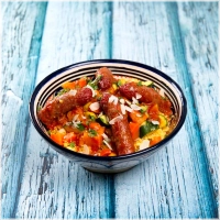 Een luchtige, gestoomde couscous, subtiel gekruid, geserveerd met lamsworstjes en geurige bouillon. Deze verrukkelijke combinatie wordt aangevuld met een rijke mix van verse groenten zoals courgette, pompoen, wortel, wittekool en zoete aardappel, samen met kikkererwten. De groenten variëren met de seizoenen<br><br>